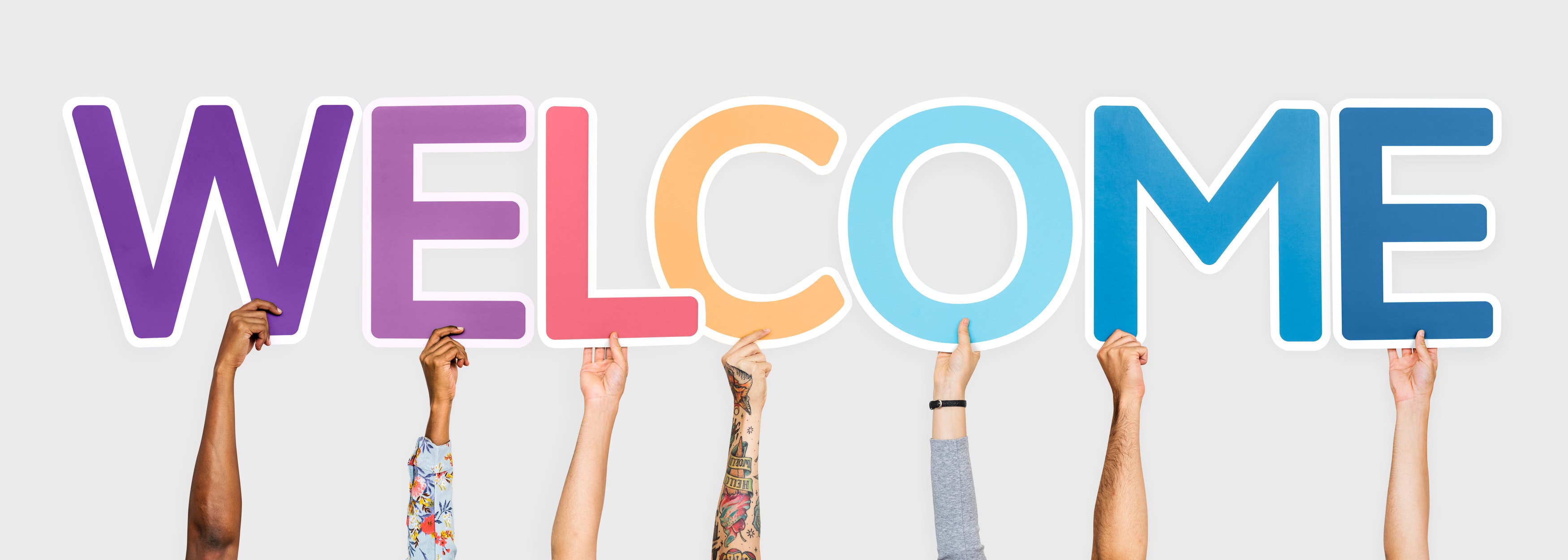 The word "welcome" spelled out with different colored letters held by different people's hands